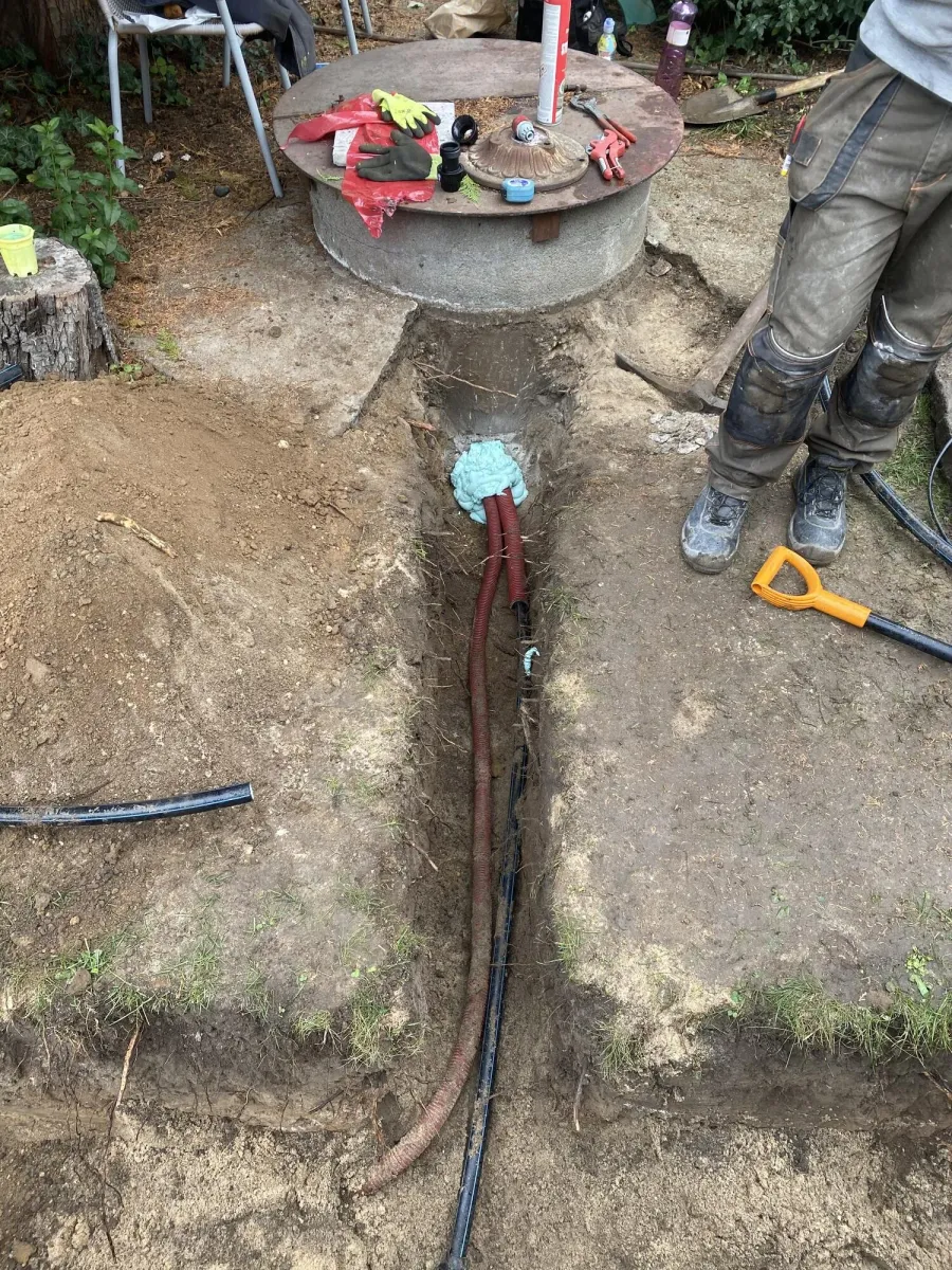Výkop s vodovodním potrubím vedeným k betonové revizní šachtě na pozemku